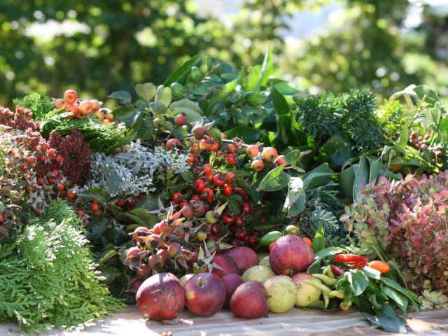 A table piled with fruit and evergreen foliage