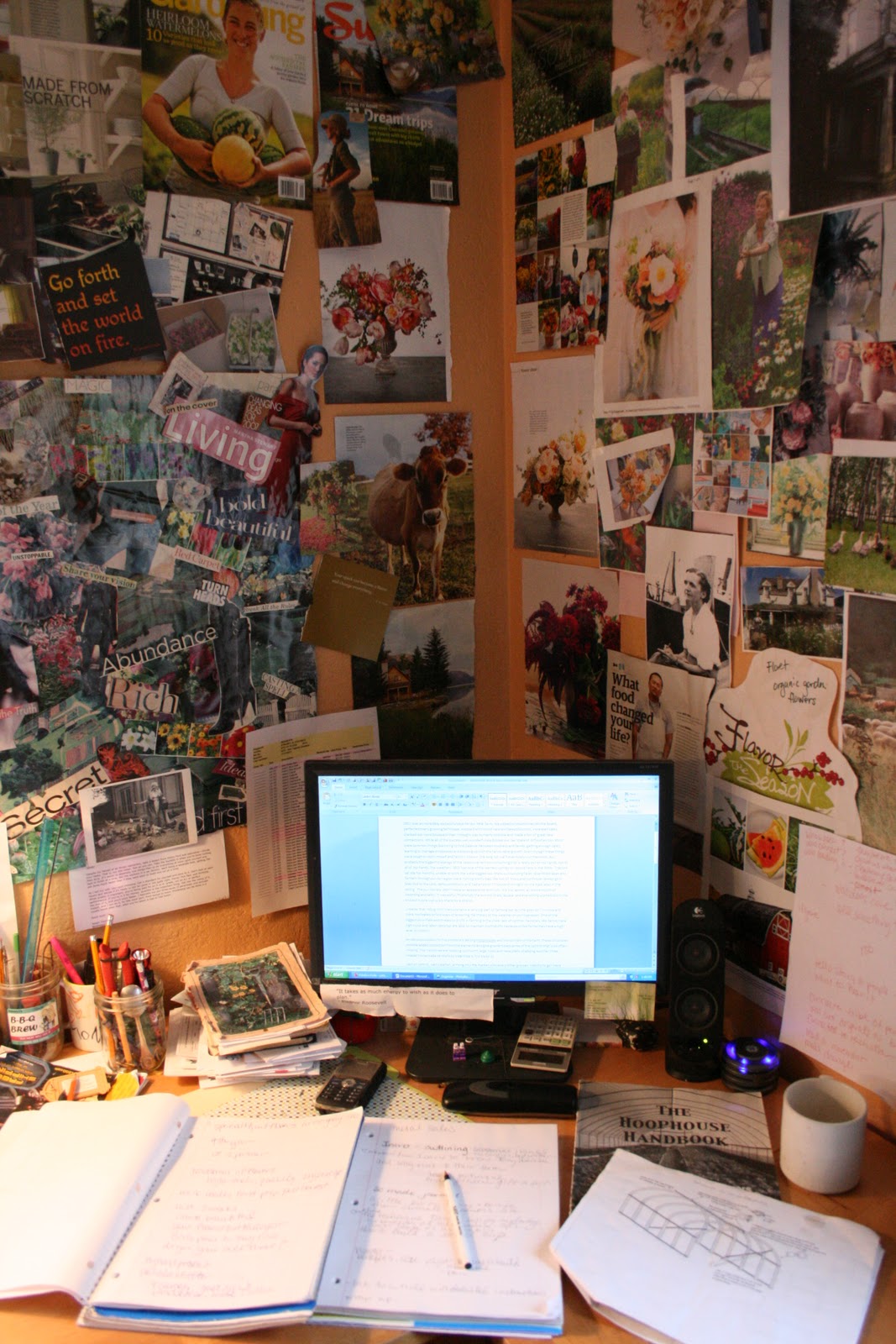 A desktop computer next to a wall covered in magazine clippings