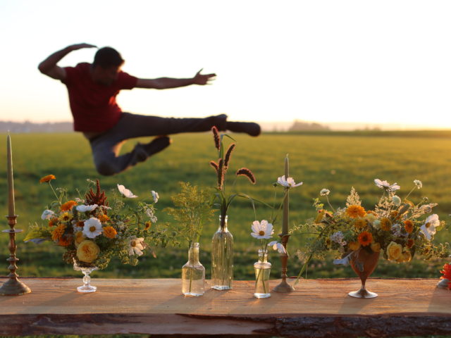 Chris Benzakein jumping midair behind flower arrangements