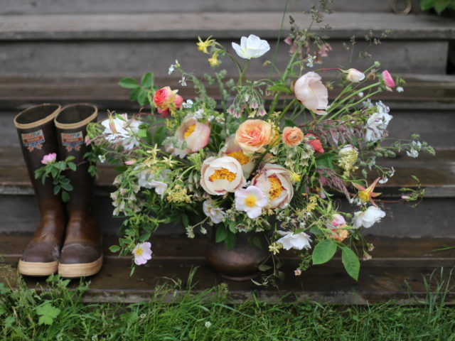 A pair of boots next to a flower arrangement