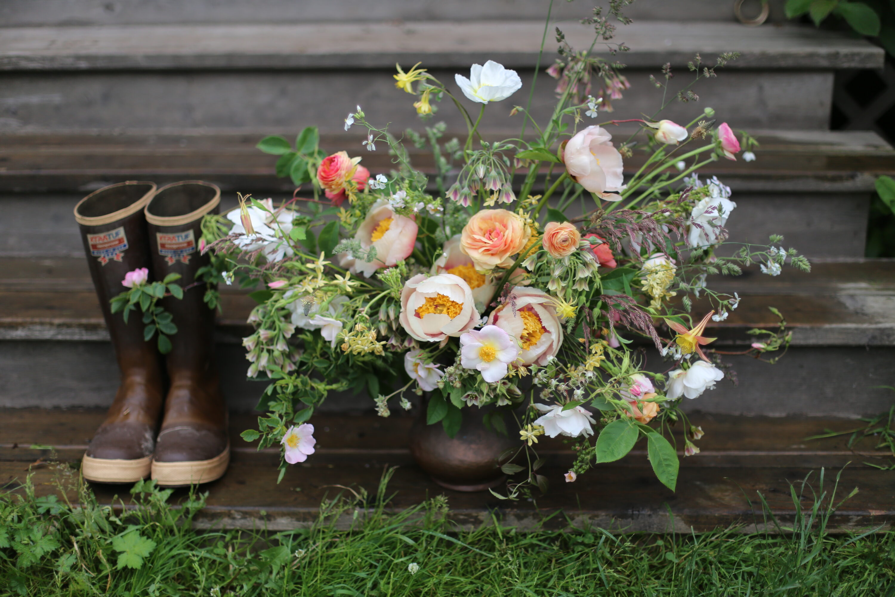 A pair of boots next to a flower arrangement