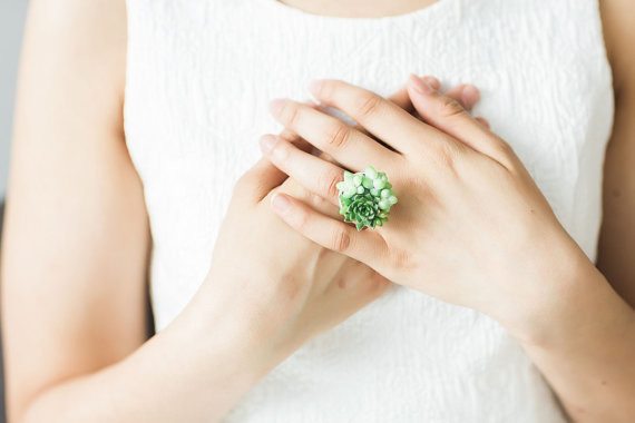 A hand wearing a ring made from succulents