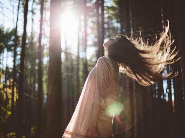 A woman flipping her hair in a forest