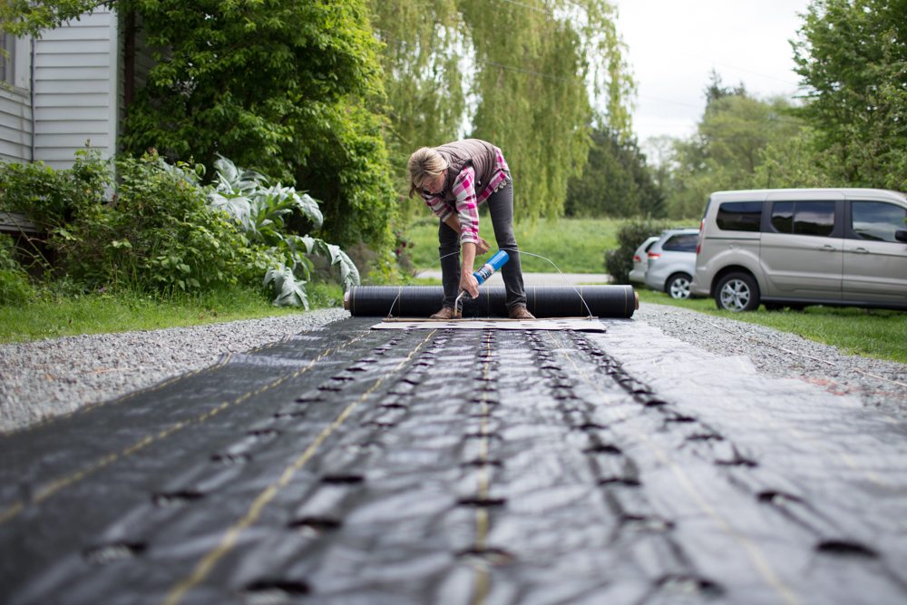 A woman burning holes in landscape fabric