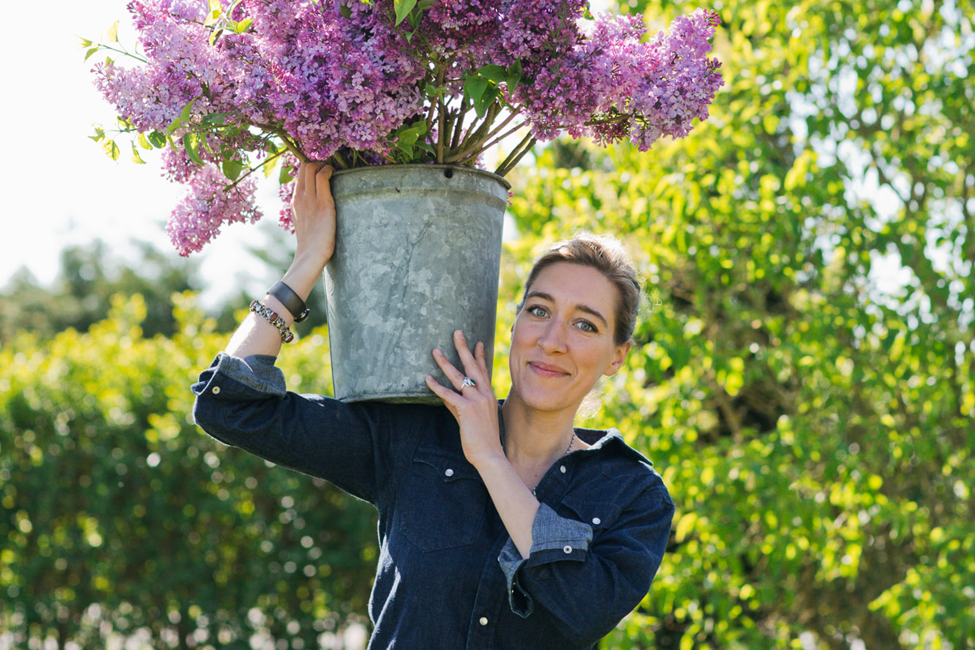 Erin Benzakein balancing a bucket of lilacs on her shoulder