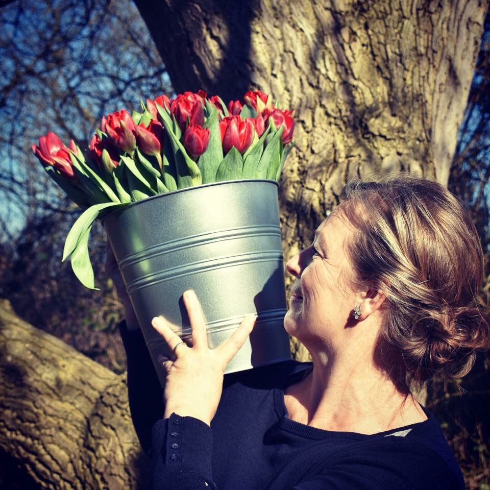 A woman holding a bucket of tulips