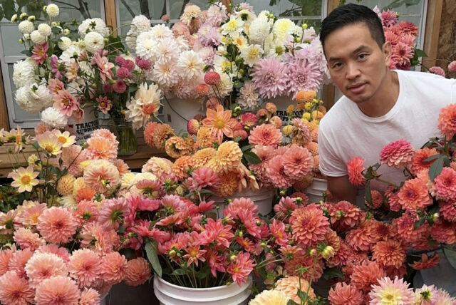 Dr. Panat surrounded by buckets of dahlias