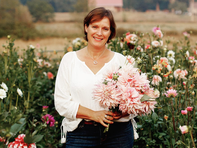 Carolyn Thompson holds a handful of dahlias in the field
