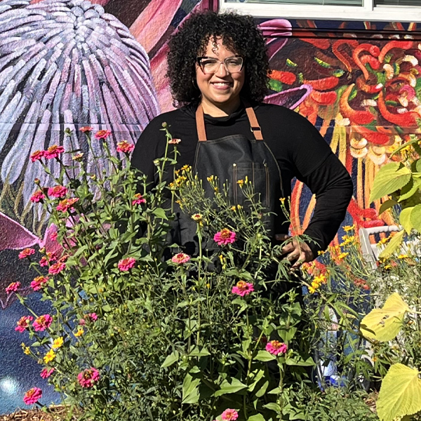 Romi Hall standing behind a patch of zinnias